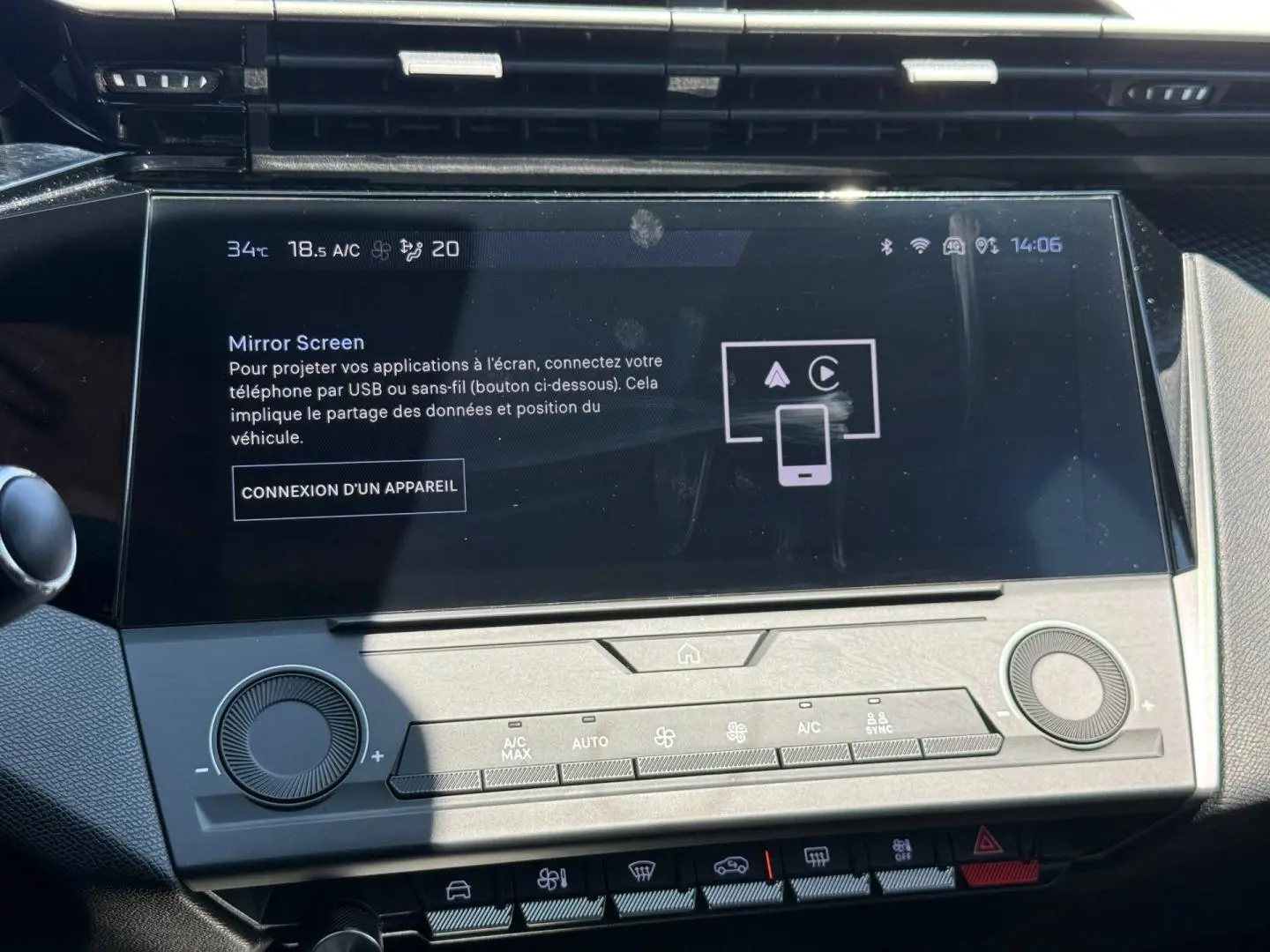 Écran tactile central de la Peugeot e-308 2025 en gros plan avec commandes climatisation et interface Mirror Screen visible.