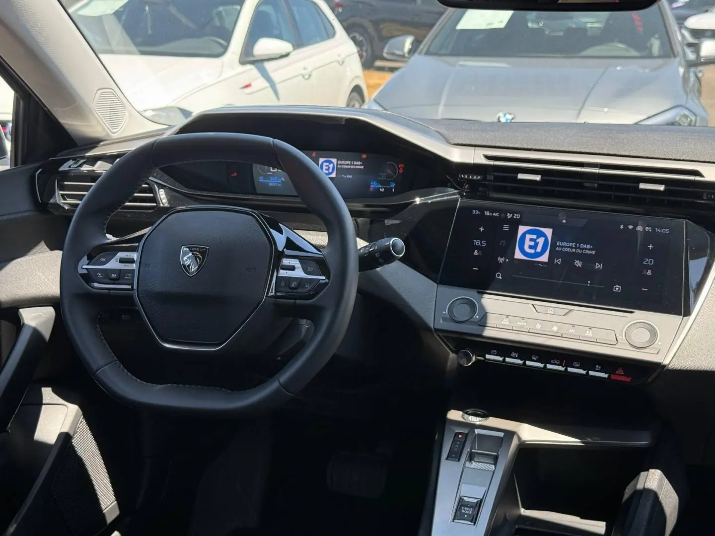 Vue intérieure du poste de conduite de la Peugeot e-308 2025, avec volant multifonction et écran tactile central.