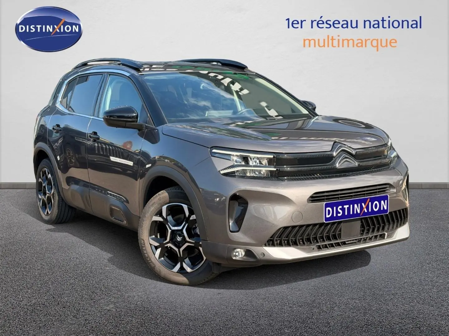Citroën C5 Aircross gris Platinium en 3/4 avant droit avec jantes alliage et barres de toit visibles.
