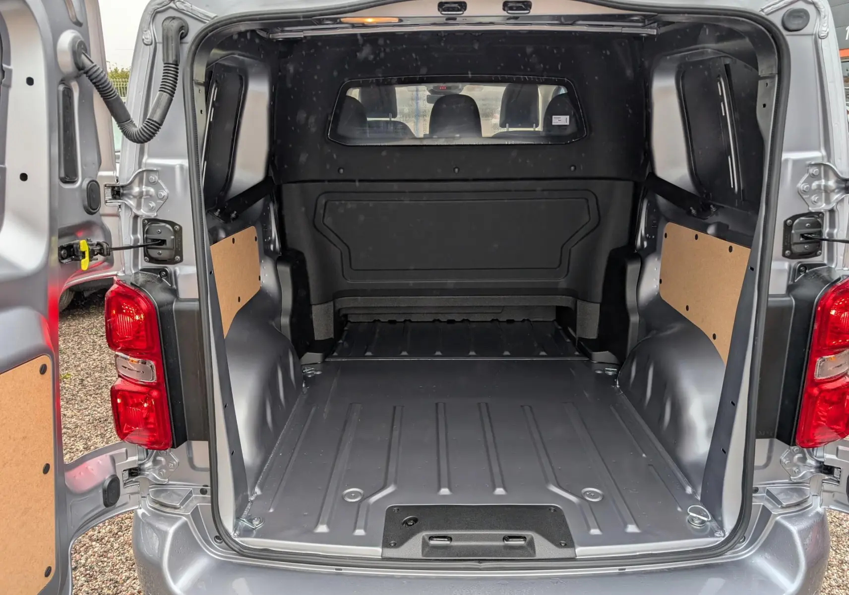 Vue arrière ouverte du Citroën Jumpy gris 2026 montrant l’espace de chargement vide et les portes battantes ouvertes.