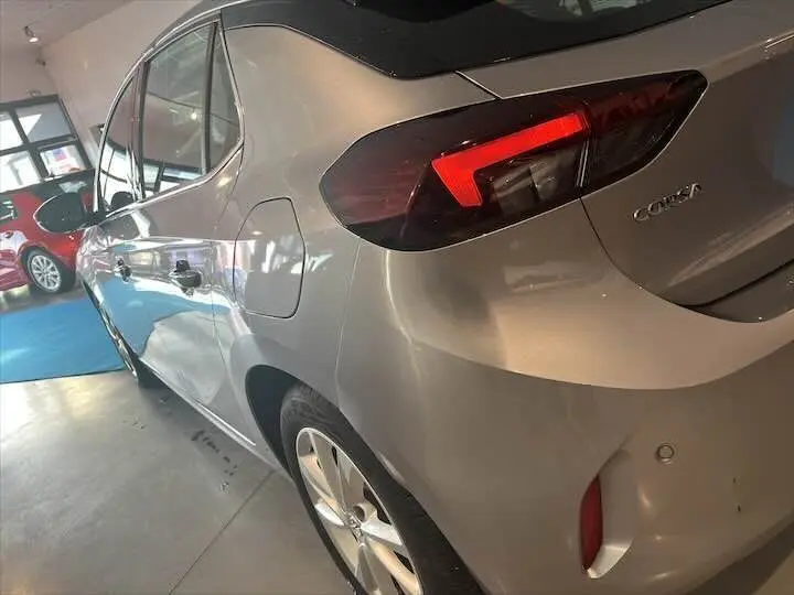 Vue 3/4 arrière gauche d'une Opel Corsa gris métal 2021 avec feux arrière LED et jantes alliage en showroom.