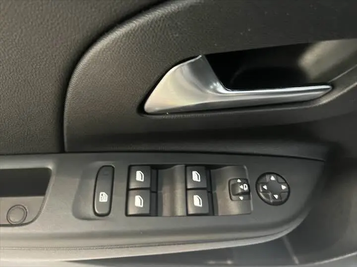 Gros plan sur la commande des vitres et poignée intérieure côté gauche d'une Opel Corsa gris métal 2021.