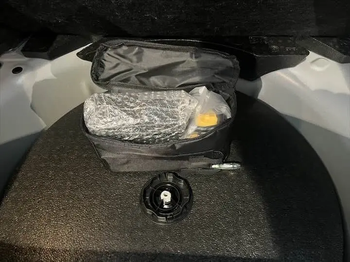 Détail du coffre d'une Opel Corsa gris métal 2021, montrant une trousse à outils noire ouverte avec des accessoires emballés.