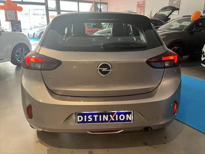 Vue arrière d'une Opel Corsa gris métal 2021 avec feux allumés et plaque Distinxion en concession.