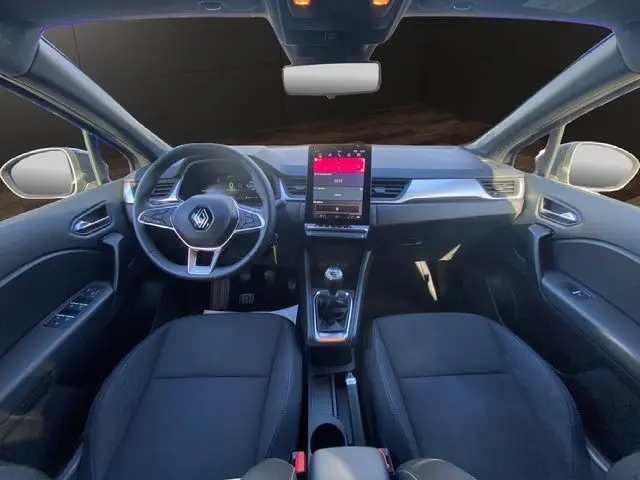 Intérieur noir du Renault Captur 2024 vu de face, tableau de bord moderne avec écran tactile vertical et volant multifonction.