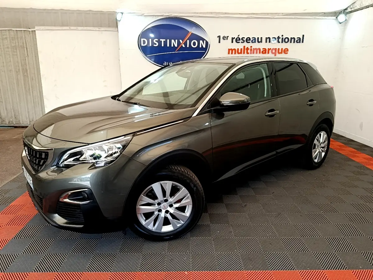 Peugeot 3008 gris foncé vue 3/4 avant droit, avec phares LED et jantes alliage visibles en intérieur showroom.