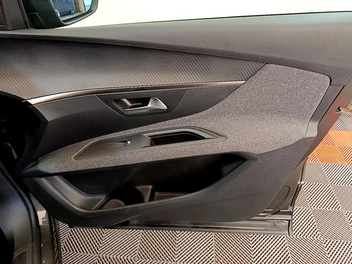Vue rapprochée de la porte côté conducteur du Peugeot 3008 gris foncé, avec habillage tissu et plastique noir.