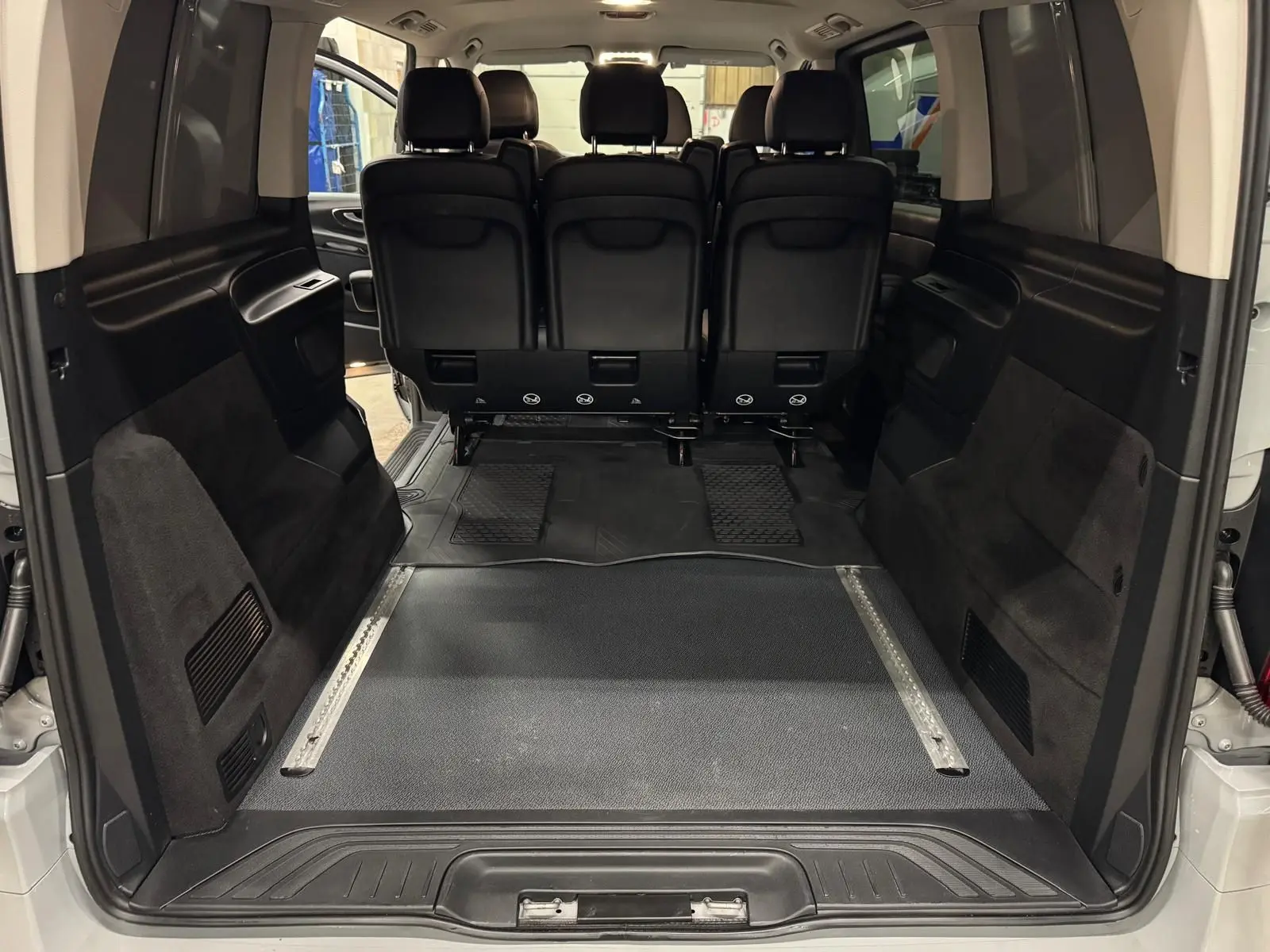 Vue arrière intérieure du Mercedes Vito Mixto gris Alpin, montrant l'espace de chargement et la banquette 3 places en cuir noir.