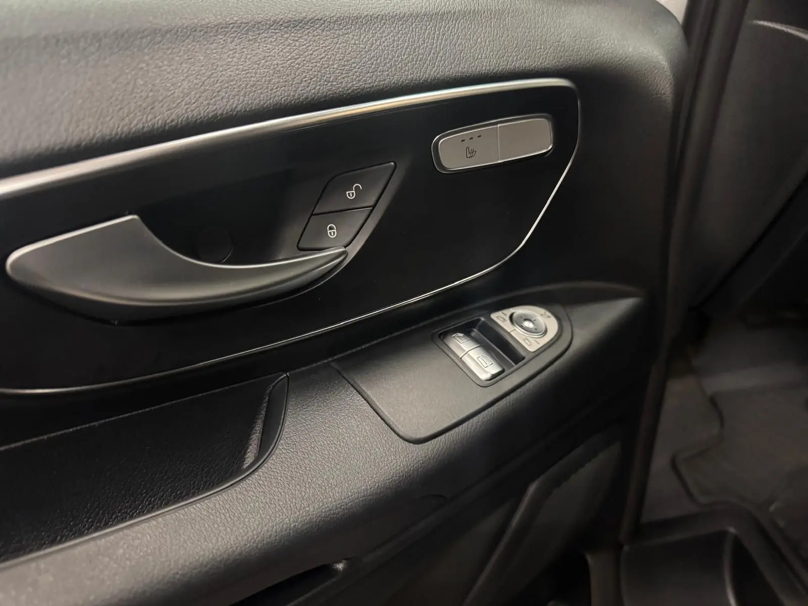 Gros plan sur la porte intérieure côté conducteur du Mercedes Vito Mixto 2025, avec commandes de vitres et bouton siège chauffant.