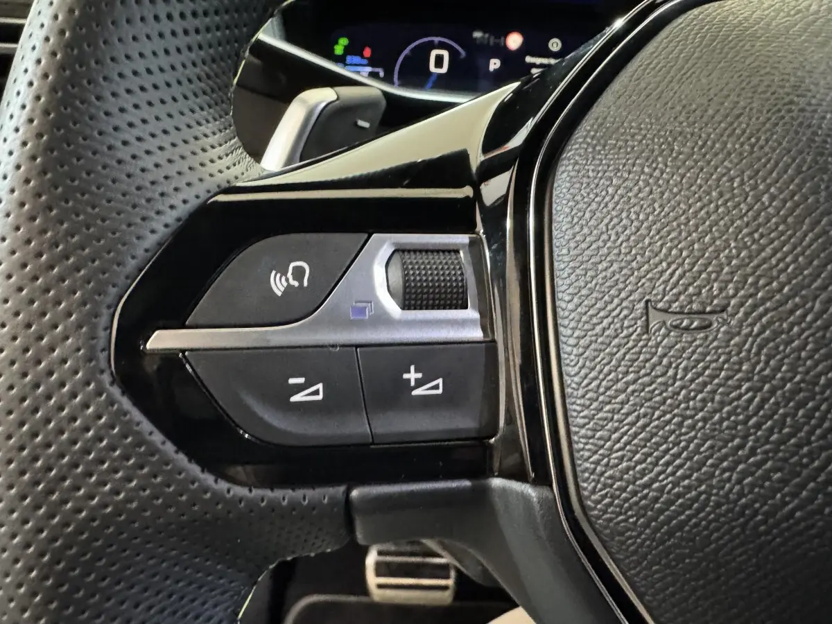 Gros plan sur les commandes gauche du volant en cuir perforé de la Peugeot 208 Hybrid 136 eDCS6 GT 2025.