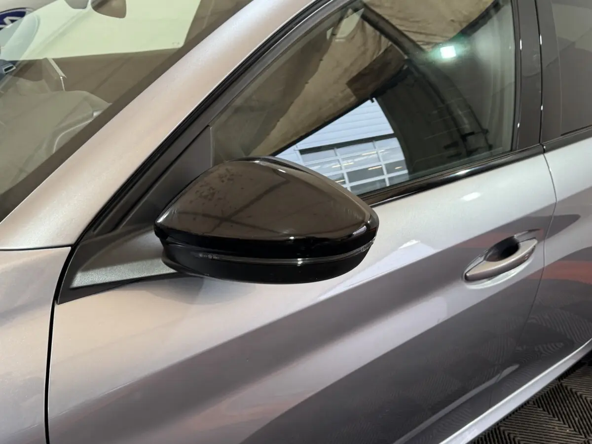 Gros plan sur le rétroviseur noir côté conducteur d'une Peugeot 208 Hybrid gris clair, vue latérale gauche.