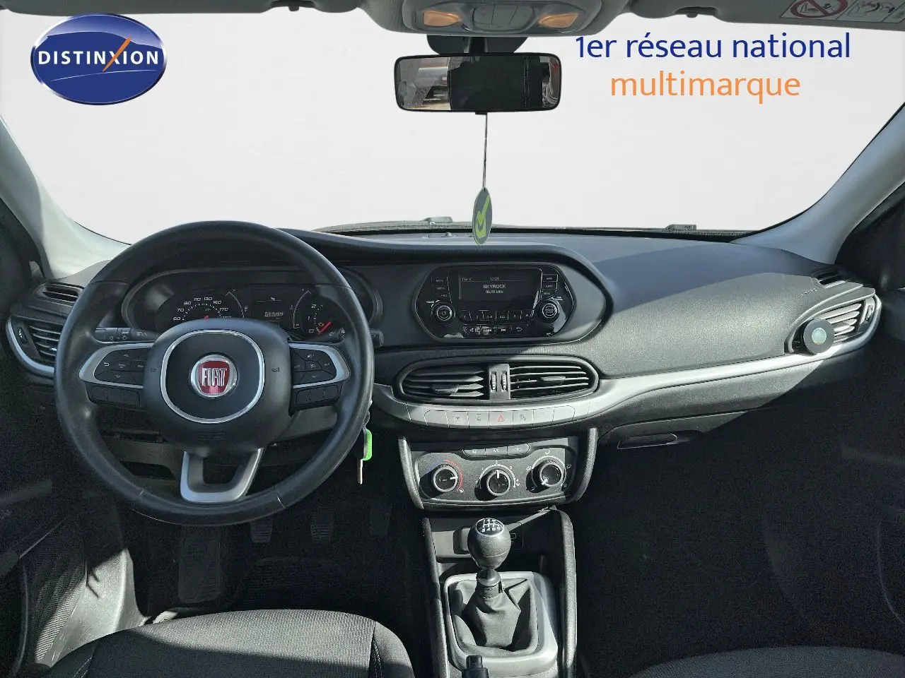 Vue intérieure avant du tableau de bord d'une Fiat Tipo 5 portes blanche de 2018 avec volant et levier de vitesses manuelle.