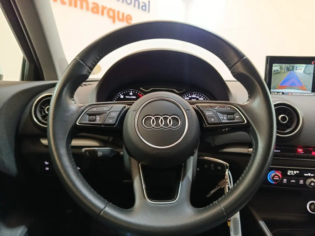Vue rapprochée du volant cuir multifonctions noir de l'Audi A3 35 TDI 150 S tronic Business Line 2020, avec tableau de bord et écran tactile.