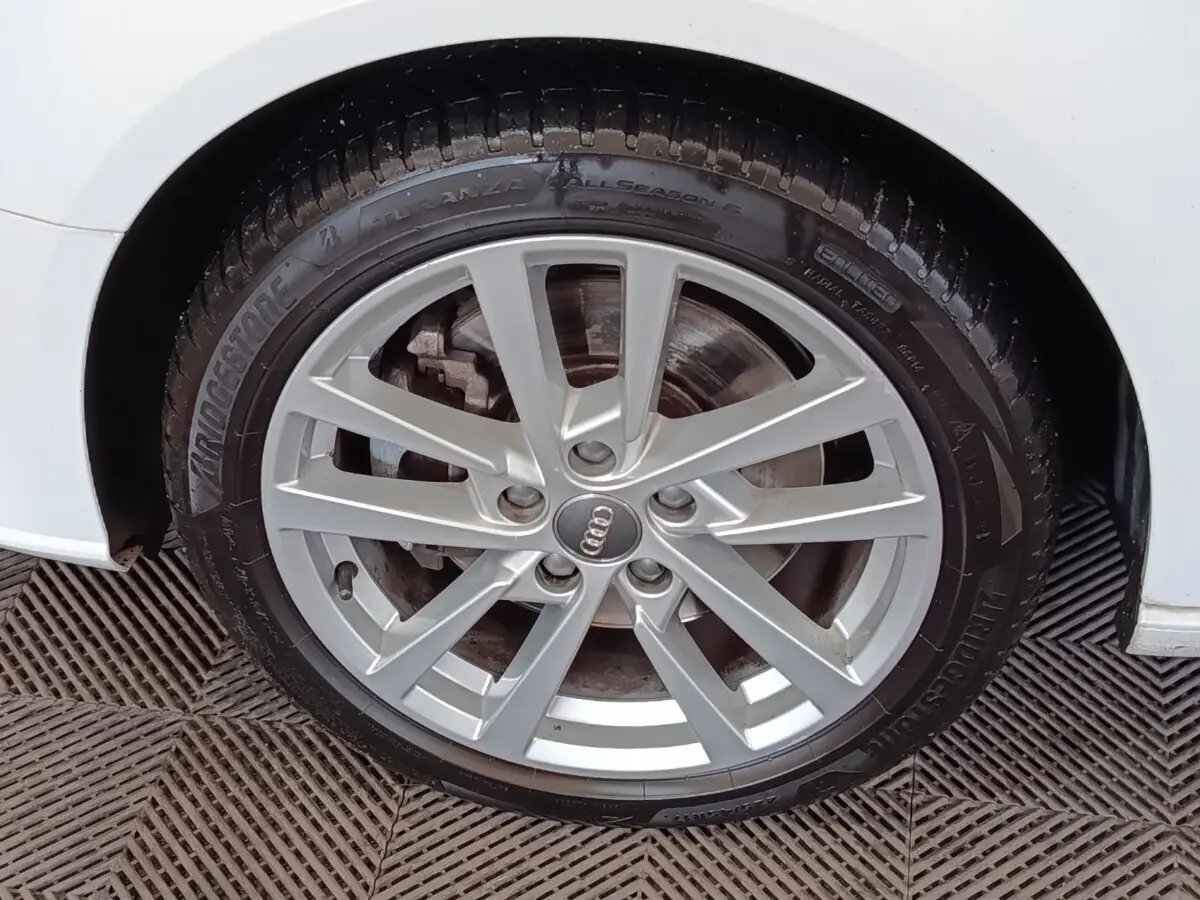Gros plan sur la roue avant droite d'une Audi A3 blanche, jante alliage à plusieurs branches fines.