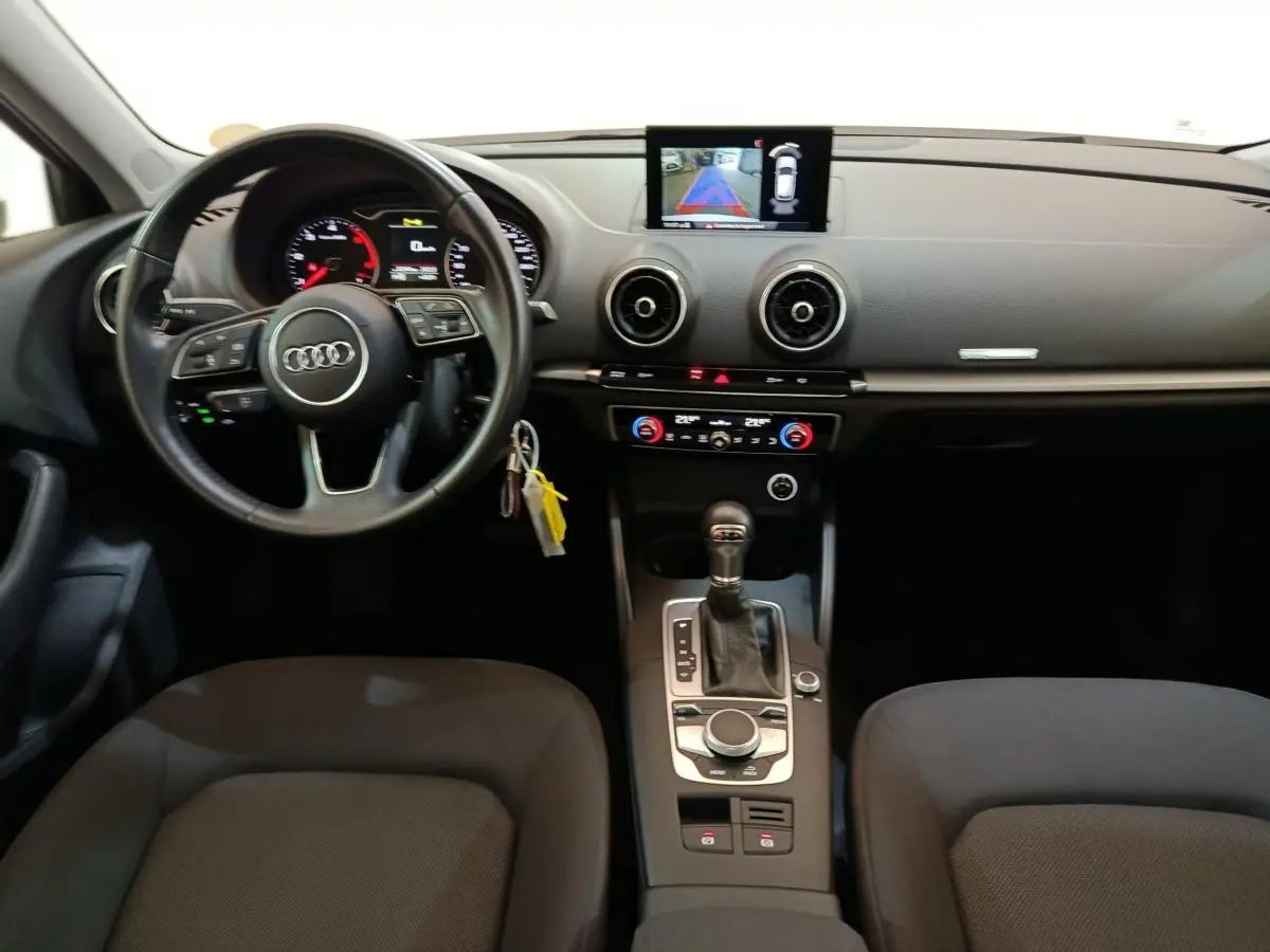 Vue intérieure avant de l'Audi A3 35 TDI 2020, tableau de bord noir avec volant cuir multifonctions et écran tactile central.