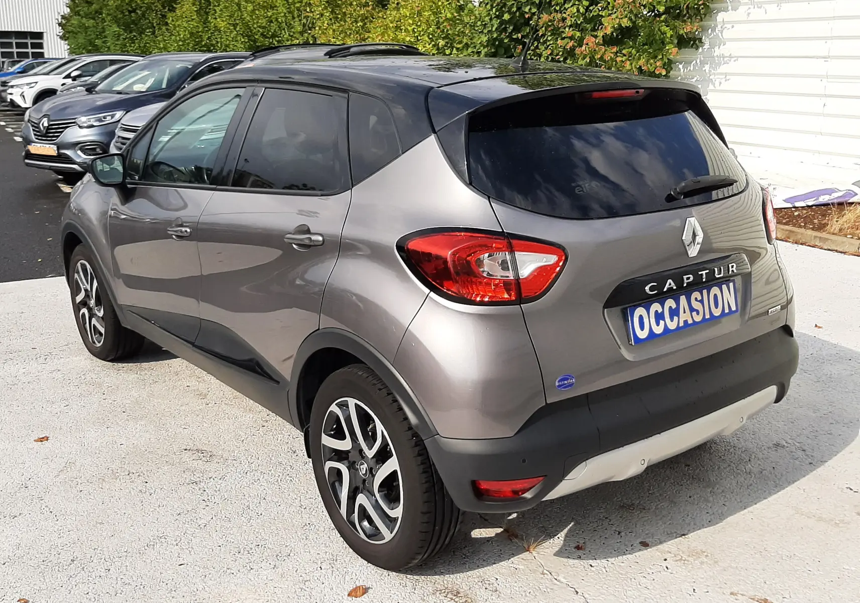 Vue 3/4 arrière droite d'un Renault Captur gris Cassiopée avec toit noir, jantes alliage et vitres teintées.