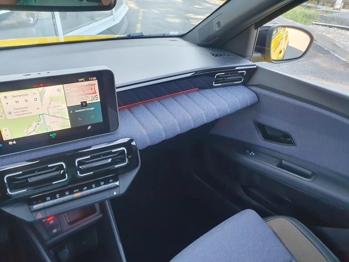 Vue intérieure côté passager de la Renault R5 E-Tech jaune, avec tableau de bord moderne et écran tactile connecté.