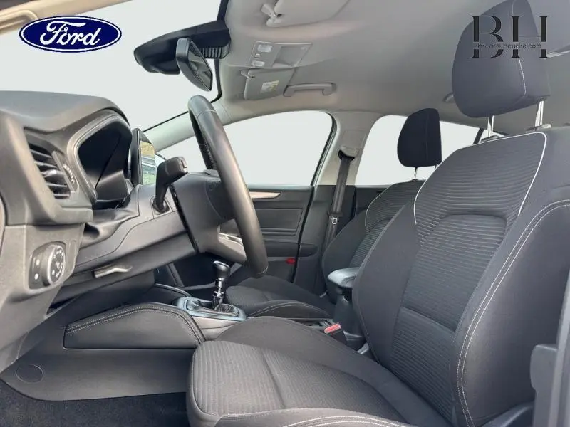 Vue intérieure côté conducteur de la Ford Focus SW 2023 avec sièges tissu noir et volant cuir multifonction.