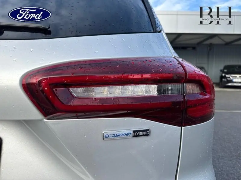 Gros plan sur le feu arrière droit gris lunaire métallisé d'une Ford Focus SW hybride avec badge EcoBoost Hybrid.