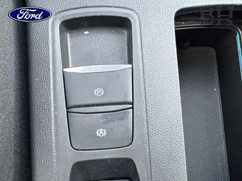 Gros plan sur les commandes de frein à main électronique et arrêt automatique du moteur de la Ford Focus SW gris lunaire.