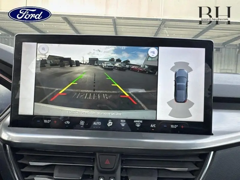 Écran tactile intérieur montrant la caméra de recul et l’aide au stationnement du Ford Focus SW gris lunaire métallisé.