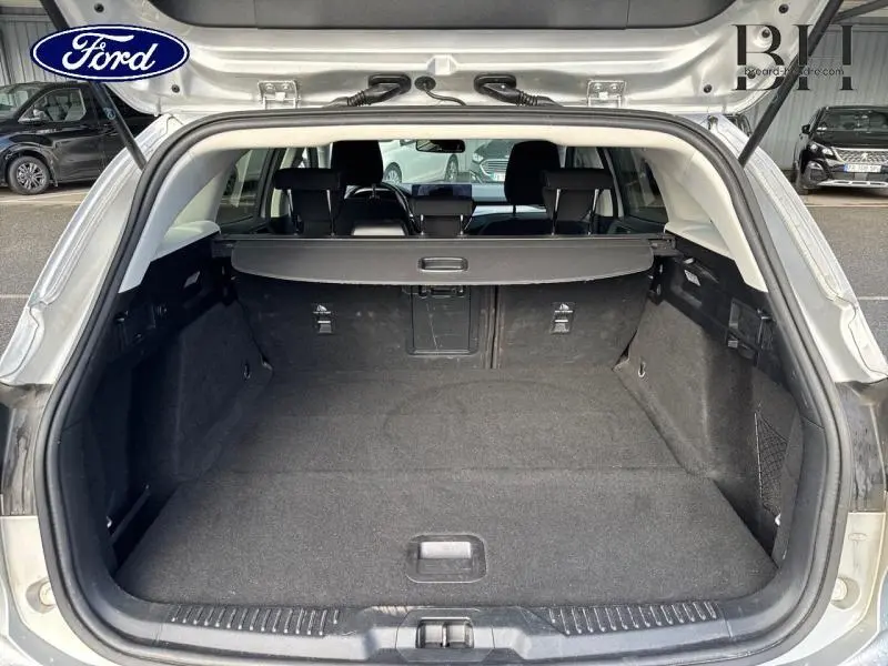 Coffre ouvert d'une Ford Focus SW gris lunaire 2023, vue arrière montrant l'espace de chargement et la plage arrière.