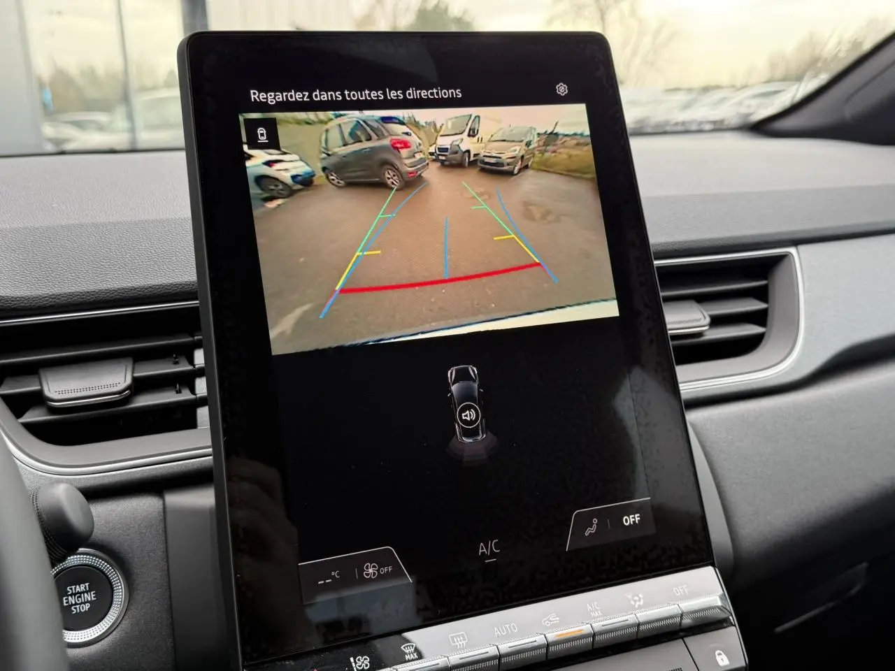Écran central du Renault Captur 2025 affichant la caméra de recul avec lignes de guidage colorées, intérieur gris.