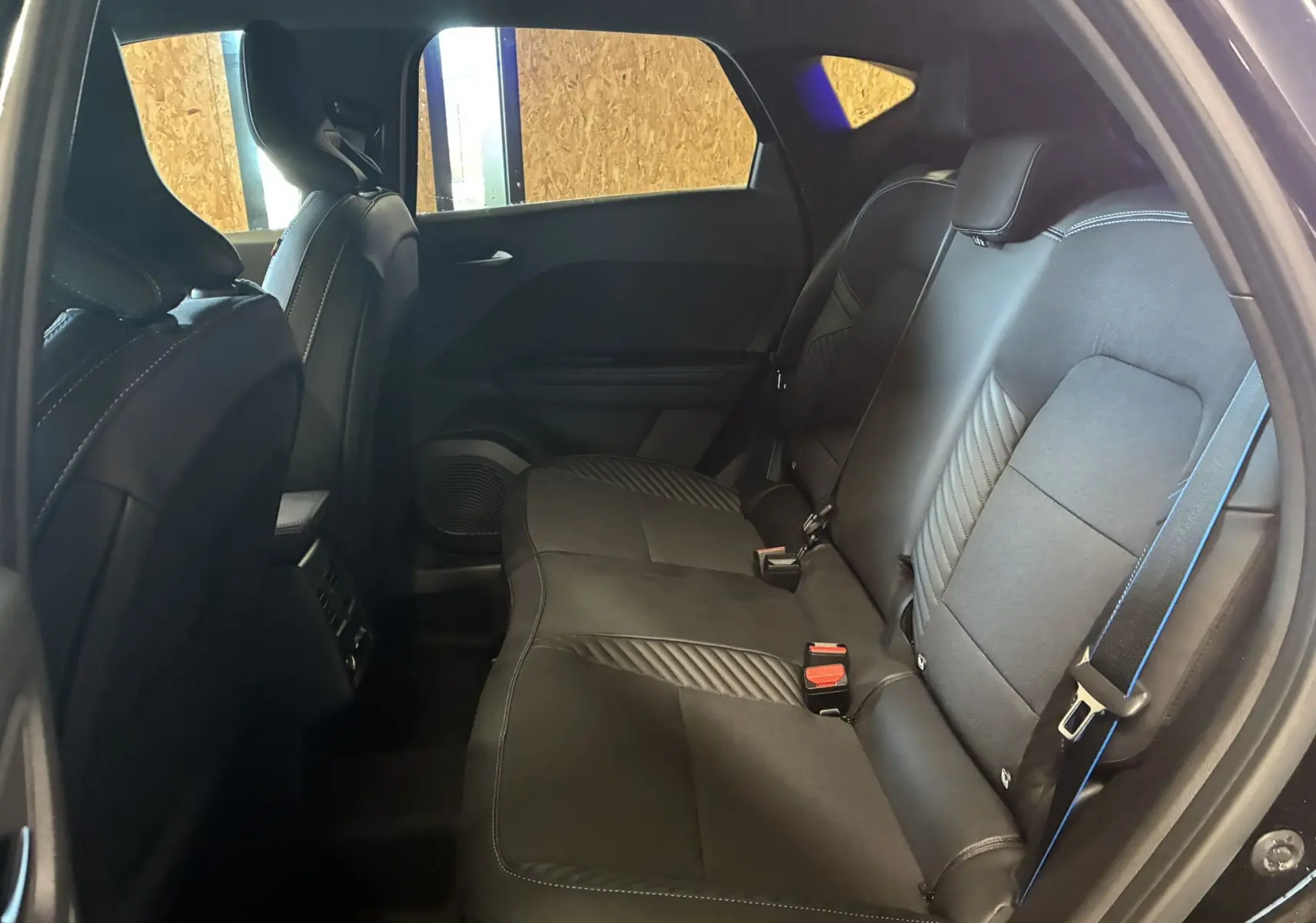 Vue intérieure côté droit des sièges arrière en cuir noir avec surpiqûres bleues du Renault Captur E-Tech 2025.