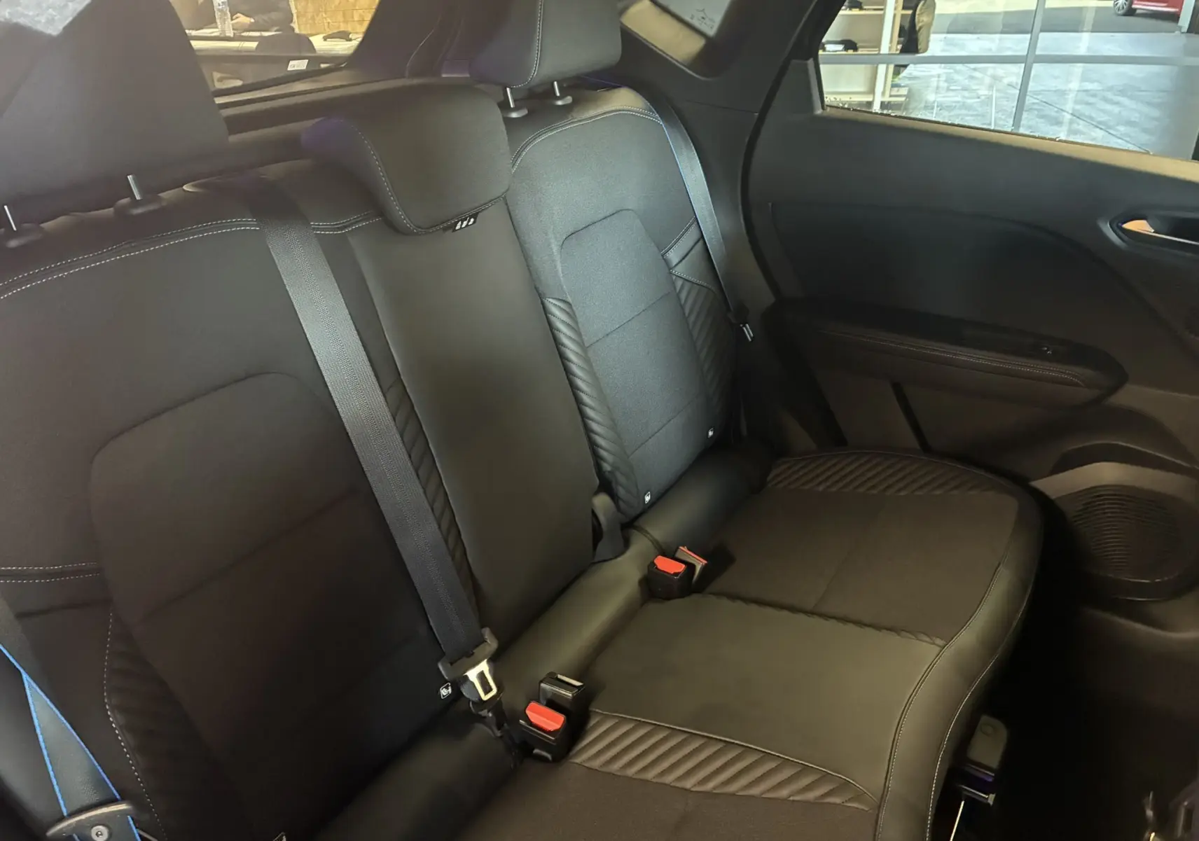 Vue intérieure des sièges arrière noirs en tissu et cuir du Renault Captur E-Tech Full Hybrid 2025, avec ceinture de sécurité visible.