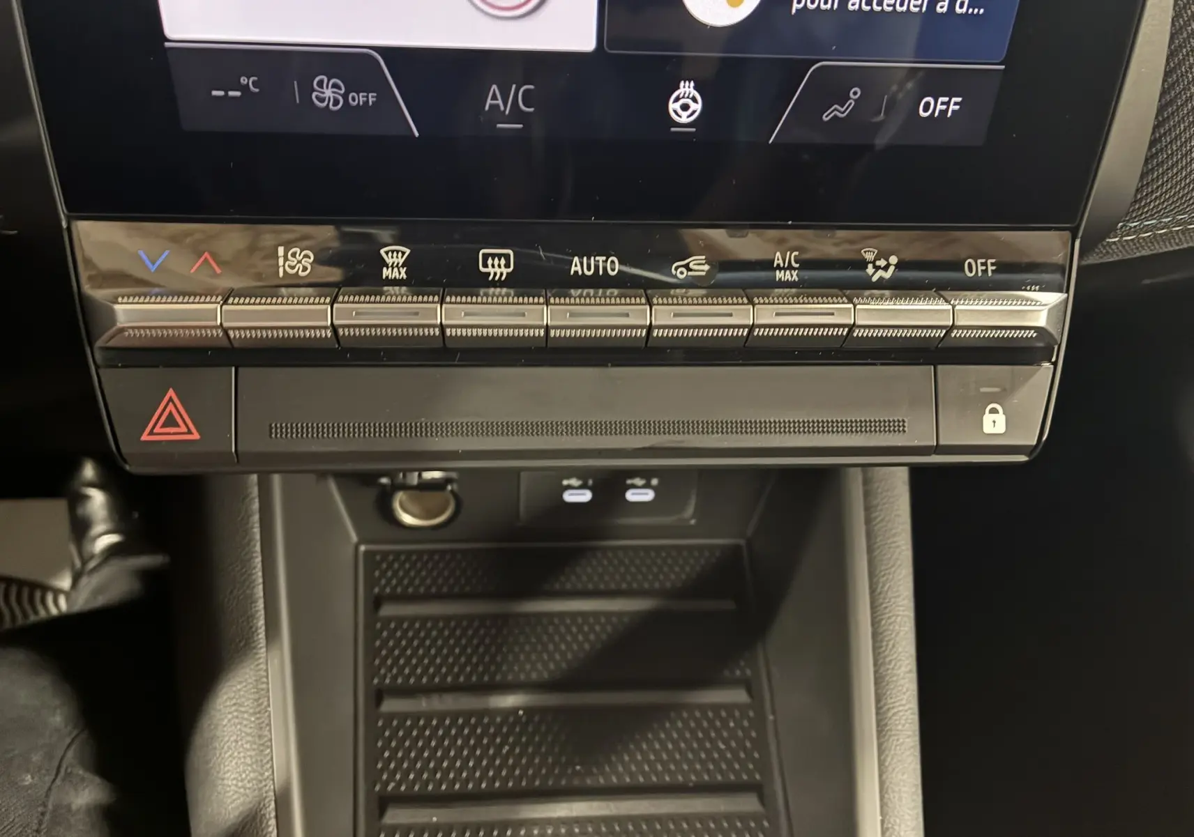 Gros plan sur la console centrale du Renault Captur E-Tech 2025, montrant les commandes tactiles de climatisation et le rangement noir mat.