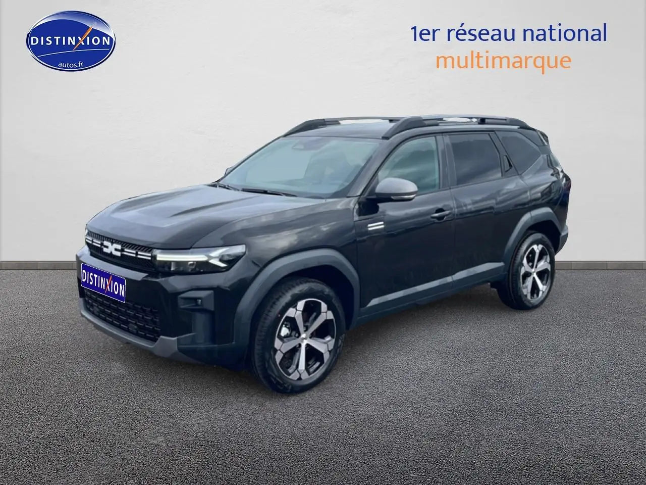 Vue 3/4 avant du Dacia Bigster noir 2025 avec jantes alliage diamantées et barres de toit visibles.