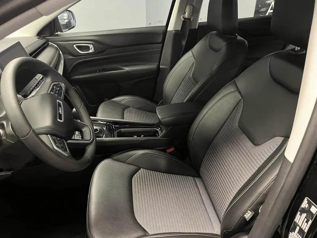 Vue intérieure côté conducteur du Jeep Compass 2024, sièges noirs mixte TEP/tissu avec surpiqûres grises et tableau de bord moderne.