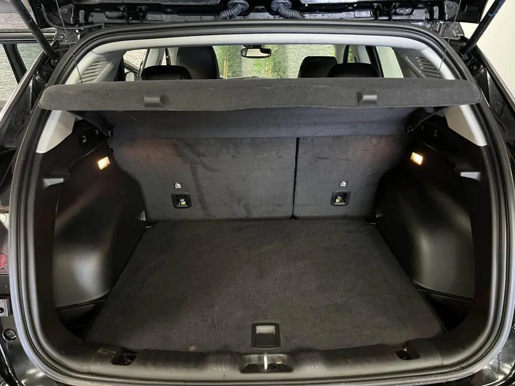 Coffre ouvert vu de l'arrière d'un Jeep Compass noir 2024, espace de chargement propre et éclairé.