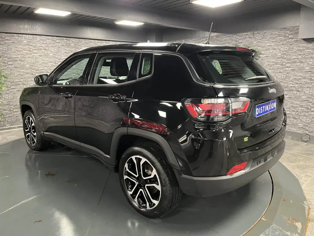 Jeep Compass noir en vue 3/4 arrière droit, avec jantes alliage noires et détails extérieurs brillants en intérieur showroom.