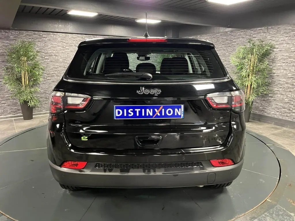 Vue arrière d'un Jeep Compass noir 2024 avec logo e-Hybrid et feux arrière LED dans un showroom.