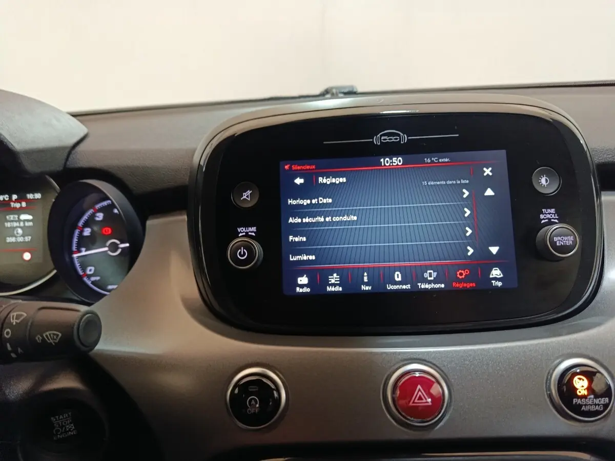 Vue rapprochée du tableau de bord de la Fiat 500X 2021, écran tactile central affichant les réglages, détails en noir et gris.