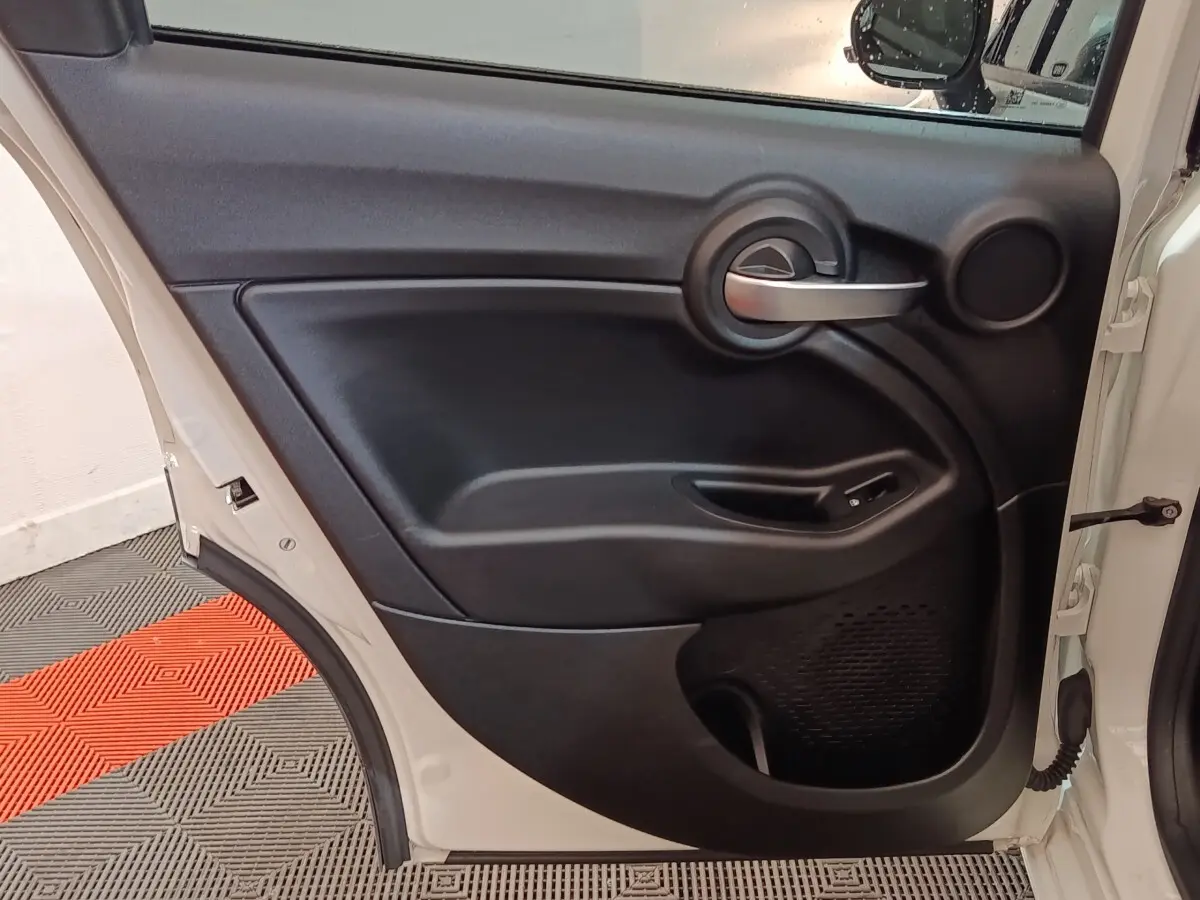 Vue intérieure de la porte arrière droite noire d’un FIAT 500X 2021 avec poignée argentée et commande de vitre.