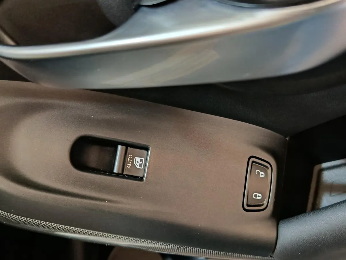 Gros plan sur les commandes de lève-vitre et verrouillage centralisé côté gauche intérieur d'une FIAT 500X noire.