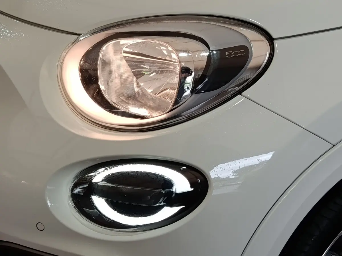 Gros plan sur le phare avant droit blanc de la FIAT 500X avec feu de jour LED en anneau lumineux.
