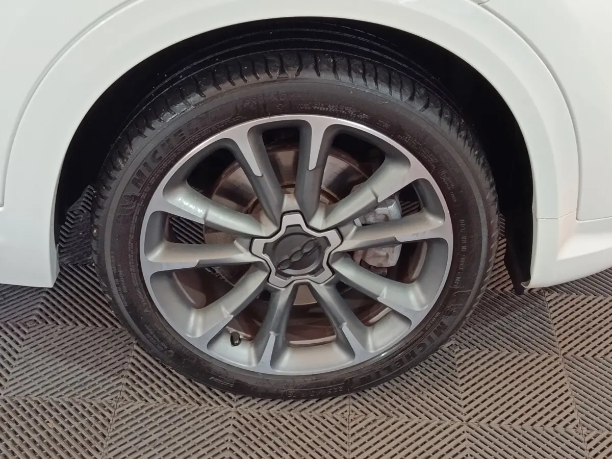 Gros plan sur la roue avant droite d'une FIAT 500X blanche, mettant en valeur la jante alliage au design moderne.