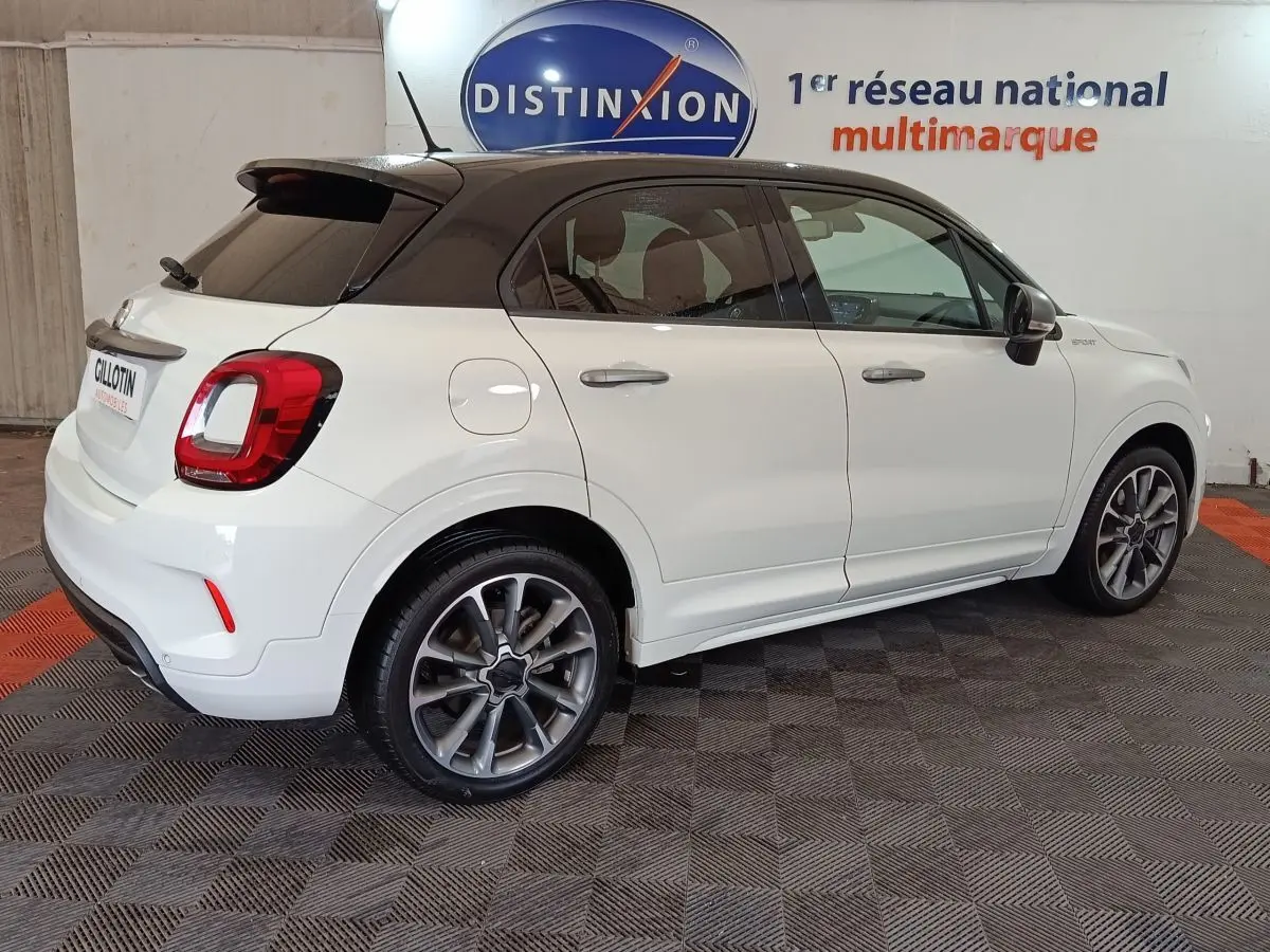 Vue 3/4 arrière droite d'une FIAT 500X blanche avec toit noir, feux arrière LED et jantes alliage sport.