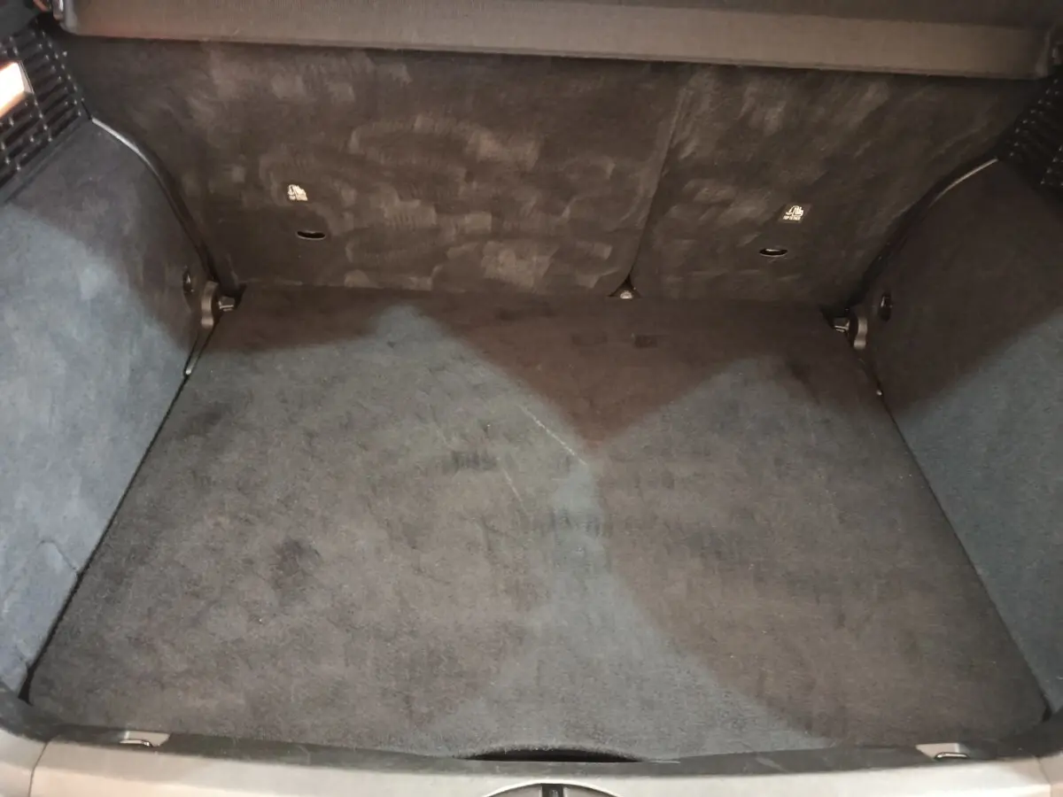 Coffre vide vu de dessus d'une FIAT 500X noir, montrant la moquette et les parois intérieures du coffre.
