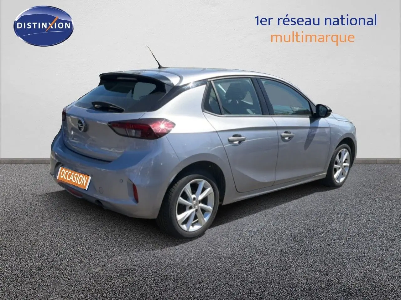 Opel Corsa gris quartz métal vue 3/4 arrière côté droit, avec feux arrière allumés et jantes alliage.