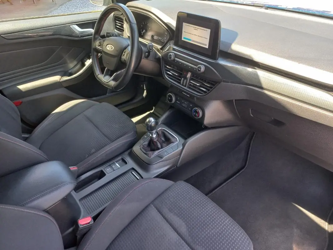 Vue intérieure côté conducteur de la Ford Focus 2019, montrant le tableau de bord, volant et levier de vitesse manuel.