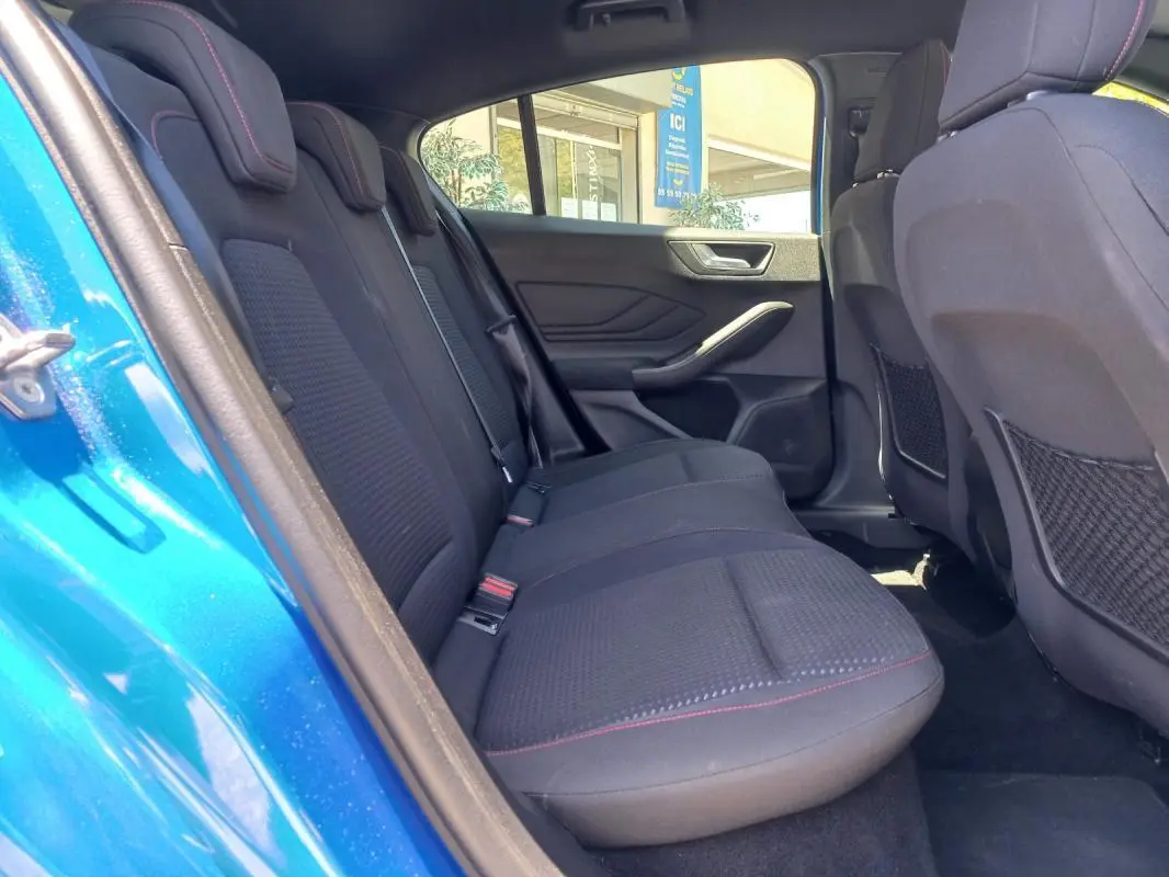 Vue intérieure arrière gauche de la Ford Focus ST-Line bleu 2019, sièges noirs avec surpiqûres rouges et portes ouvertes.