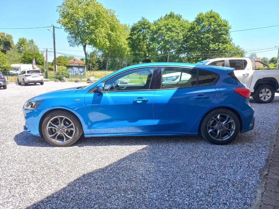 Vue de profil côté gauche d'une Ford Focus 2019 bleue ST-LINE avec jantes alliage et carrosserie compacte.