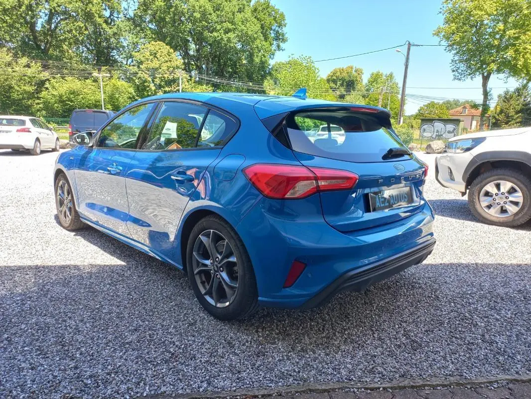 Vue 3/4 arrière droite d'une Ford Focus bleue 2019 version ST-LINE avec jantes alliage et hayon distinctif.