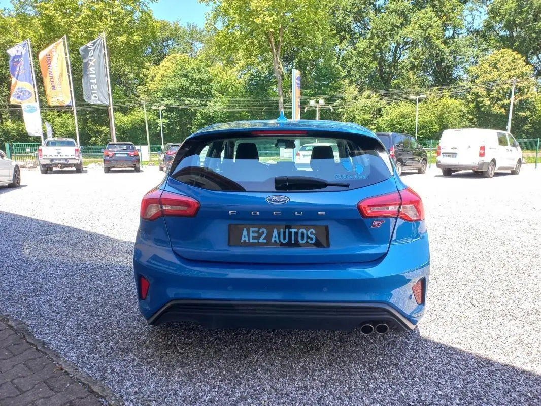 Vue arrière d'une Ford Focus ST-Line bleu vif, avec double sortie d'échappement et logo ST visible.