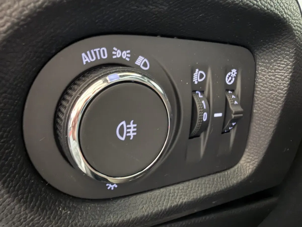 Gros plan sur la molette de réglage des phares et des feux antibrouillard dans l’habitacle de l’Opel Corsa gris clair 2025.