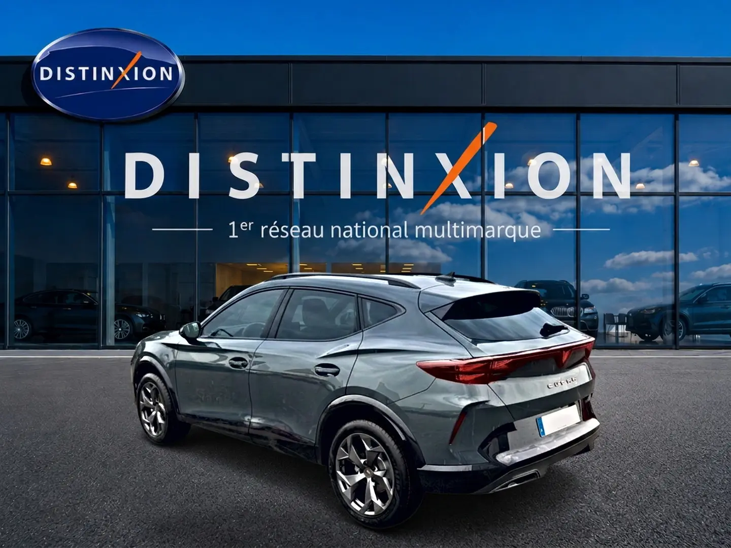 Vue 3/4 arrière droite d'un CUPRA Formentor gris métallisé avec feux arrière LED et jantes 18 pouces devant un showroom.